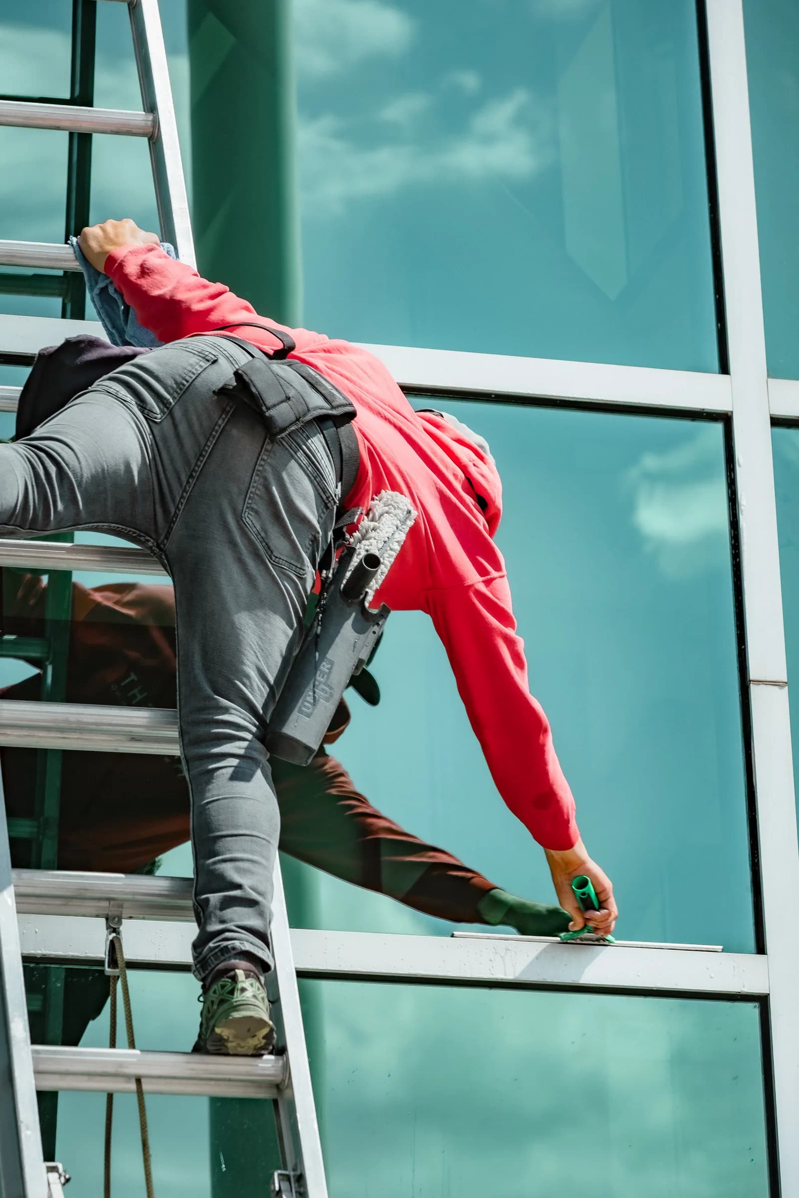 Sonlight technician rappelling on a glass tower in a Sonlight uniform — Englewood, Colorado
