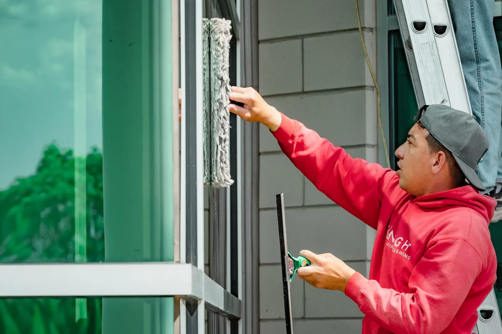 Sonlight technician scrubbing a commercial window with a strip washer — Erie, Colorado
