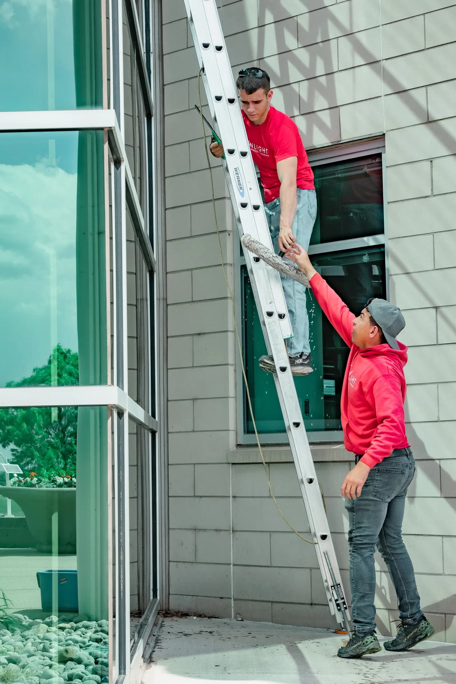 Two Sonlight technicians with extension ladder against a commercial building — Windsor, Colorado