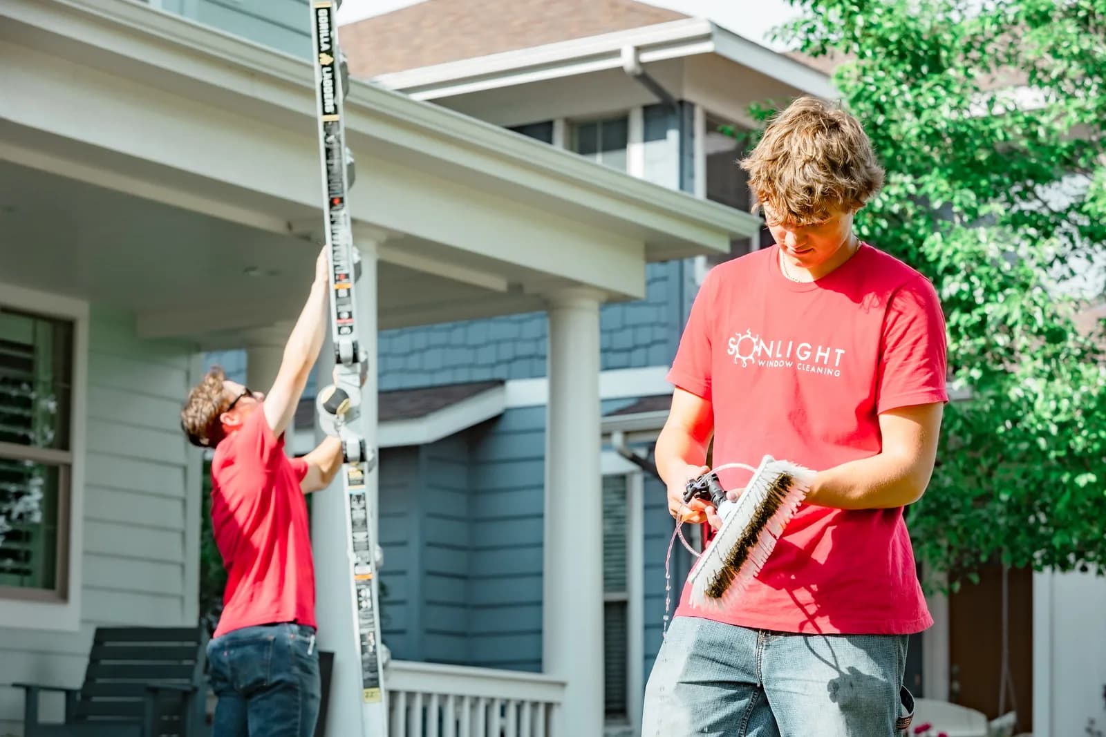 Sonlight crew cleaning windows on a suburban Colorado home with blue siding — Windsor, Colorado